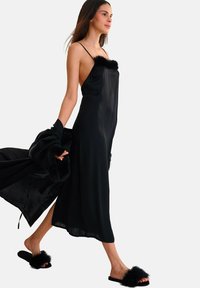 Robe de nuit en satin noir avec une texture transparente, ornée d'accents en fausse fourrure noire au niveau du col et des ourlets, accompagnée de sandales à glissière en fourrure noire.