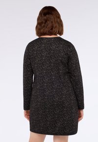 Rochie cu mânecă lungă, de culoare neagră, cu un model de leopard, design ajustat și decolteu rotund, realizată dintr-un material moale și texturat.