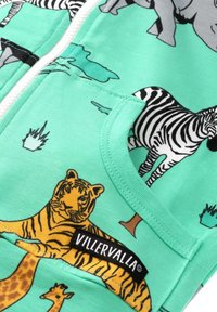 Mintgrön zip-up hoodie med djurtryck, inklusive tigrar och zebror, med en vävd etikett som säger "VILLERVALLA." Mjuk, bomullstyg.