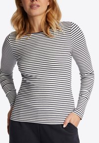 Langsleeve top van ribbelstof met horizontale zwart-witte strepen. De top heeft een ronde halslijn en een getailleerd silhouet.