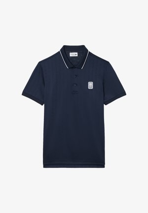 Granatowa koszulka polo wykonana z oddychającej tkaniny o teksturowanym wzorze, z plisą na trzy guziki oraz kontrastującym białym kołnierzem i wykończeniami rękawów.