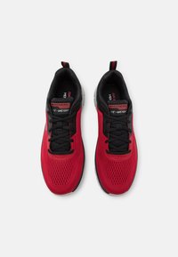 Röda sportskor med ett ventilerande mesh-övre, svarta detaljer och snören. Utrustad med en strukturerad sula och förstärkt häl. Dubbel logotyp på tungan.