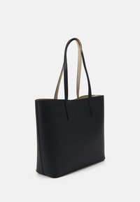 Black tote bag with a smooth textured finish, featuring long flat handles and a minimalist design. Interior shows a contrasting beige lining.