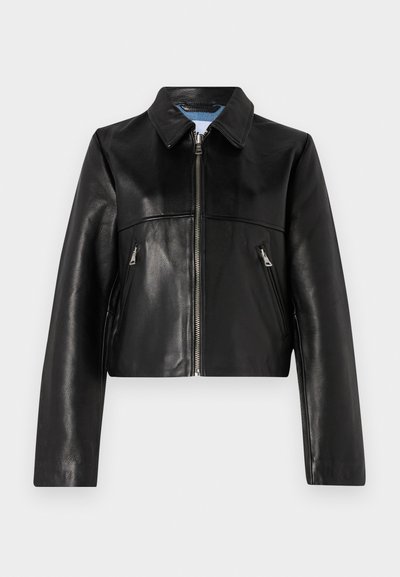 Veste courte en cuir noir avec fermeture éclair, col pointu et deux poches zippées à l'avant. Texture lisse avec des détails de design minimalistes.