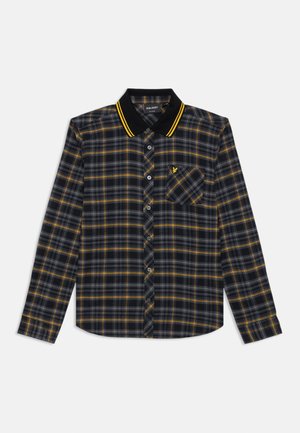 Tumši pelēks un dzeltens svītrots krekls ar garām piedurknēm, melna apkakle ar dzeltenām svītrām, pogu aizdare priekšā un krūšu kabata ar logo izšuvumu.