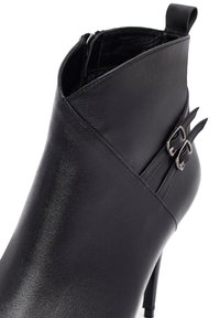 Schwarze Knöchelstiefel aus glattem Leder, mit einem hohen Absatz, einem gespaltenen Design oben und doppelten Schnallenakzenten an der Seite.