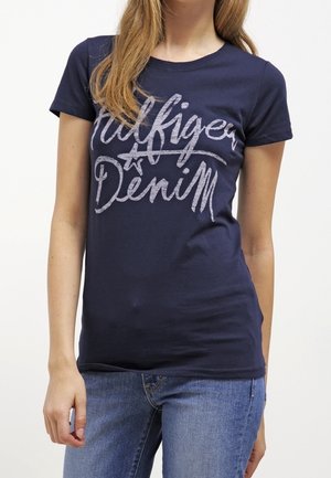 Granatowy bawełniany t-shirt z srebrnym napisem "Hilfiger Denim" na piersi. Dopasowany krój, krótkie rękawy i okrągły dekolt.