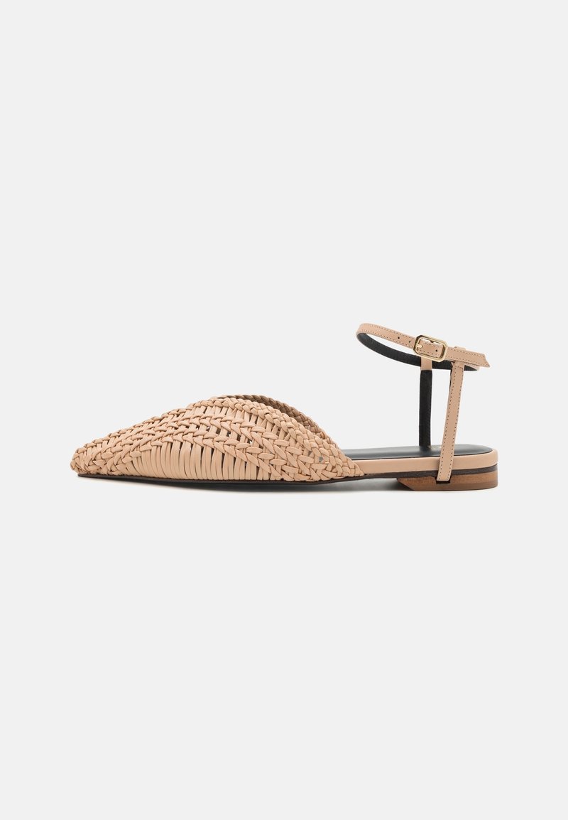 Sandale plate tissée beige à bout pointu avec bride cheville et boucle dorée, semelle intérieure noire, et talon bas en bois sur fond blanc.
