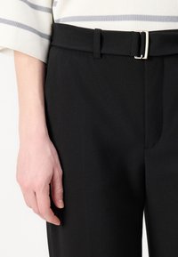 Black pants with a smooth texture and a slim fit, featuring a narrow belt, silver buckle, and a subtle seam detail on the front.