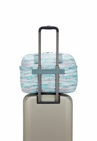 Blauwe en witte tas met een palmbladerenpatroon, gemonteerd op een zilveren koffer met uitschuifbare handgreep, zichtbare textielen banden.