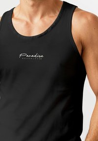 Schwarzes Tanktop mit rundem Ausschnitt, das auf der Vorderseite ein weißes, geschwungenes Logo "Paradise NEVERTHELESS" trägt. Hergestellt aus glattem Stoff.