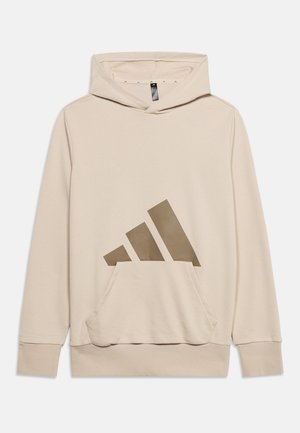Sweat à capuche beige avec poche kangourou à l'avant et grand logo penché à trois bandes marron sur le devant au centre.