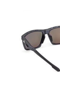 Svarta solglasögon med en geometrisk ram, mörkt tonade linser, gummidetaljer och raka skalmar som är utformade för en säker passform under aktiviteter.