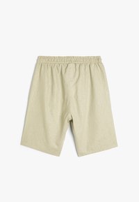 Lys beige shorts med elastisk talje, lavet af et struktureret stof. Designet har en løs pasform og en knælang længde.