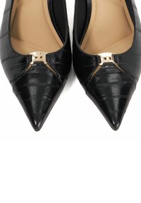 Black pointed-toe leather flats with textured pattern and gold metal buckle detail on the front, beige inner lining visible.
