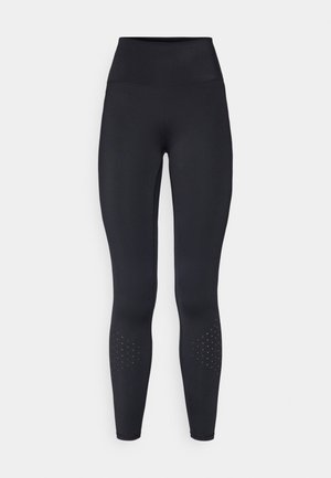 Leggings negros de cintura alta hechos de un material elástico, con una textura suave y acentos de diseño perforado cerca de los tobillos.