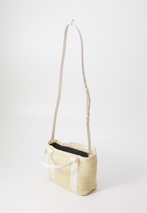 Kleine rechthoekige beige geweven handtas met witte handvatten en lange verstelbare schouderriem, open bovenkant met zwarte voering.