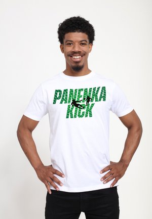 Homme souriant, mains sur les hanches, portant un T-shirt blanc avec le texte vert "PANENKA KICK" et des silhouettes de joueurs de football.