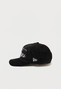 Boné de basebol preto com acabamento texturizado, apresentando letras brancas bordadas e um detalhe de logotipo na lateral. Aba curva, tira ajustável.