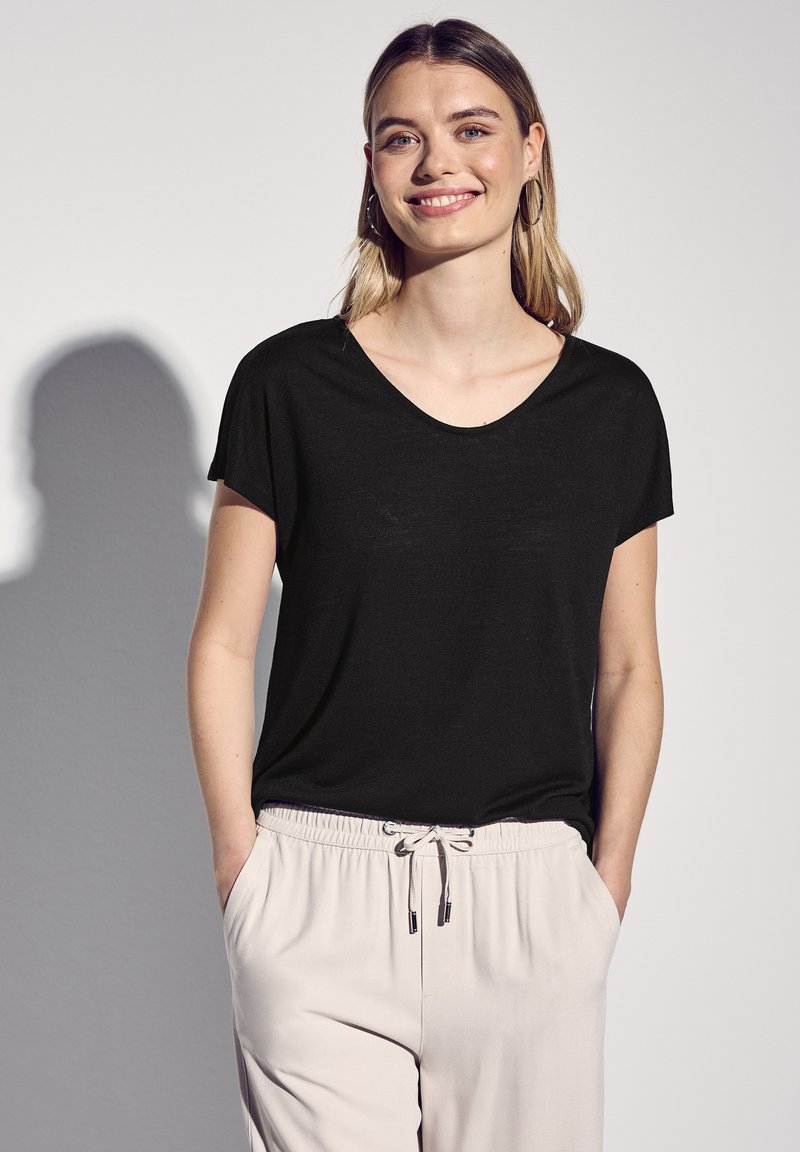 T-shirt nero con scollo a V realizzato in tessuto morbido, progettato con maniche corte. Abbinato a pantaloni beige chiaro con vita elastica e cordino.