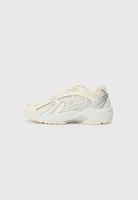 Beige and silver sporty sneaker with mesh panels and white sole, shown from the side on a plain light background.