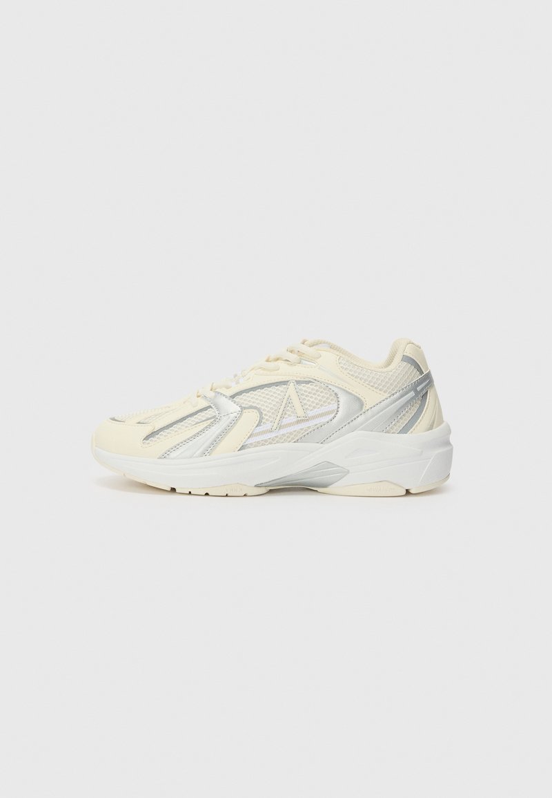 Beige and silver sporty sneaker with mesh panels and white sole, shown from the side on a plain light background.