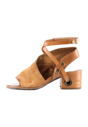 Sandale ouverte en daim et cuir couleur tan avec lanières croisées autour de la cheville et petit talon carré, vue de profil sur fond blanc.