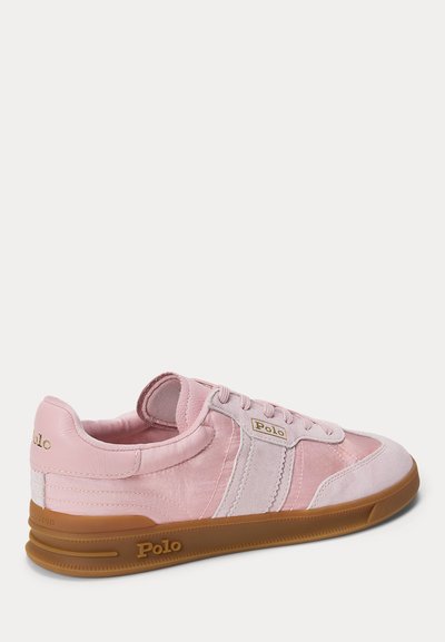Rozā Polo sporta apavi ar zamšādas akcentiem, gumijas zoli un "Polo" logotipu uz sāniem un papēža, redzami no sāniem, vērsti pa labi.