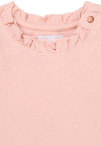 Rosa Baumwolloberteil mit Rüschenausschnitt, verziert mit gestickten Blumen- und Wellenmustern. Enthält ein kleines Knopfdetail am Kragen.