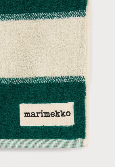 Крупен план на зелено-бяла кърпа с ивици с платнен етикет, на който пише "marimekko", пришит на зелената ивица.