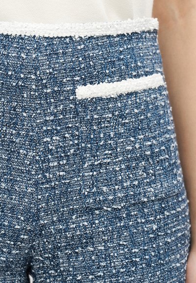 Κοντινό πλάνο σε μπλε και λευκό υφή ύφασμα τουίντ παντελονιού με λευκή επένδυση στη τσέπη και τη μέση.