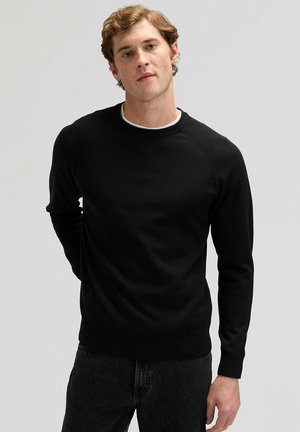 Czarny dzianinowy sweter z okrągłym dekoltem, długimi rękawami, ściągaczami na mankietach i dole. Gładka faktura, dopasowany krój, noszony na białej koszuli.