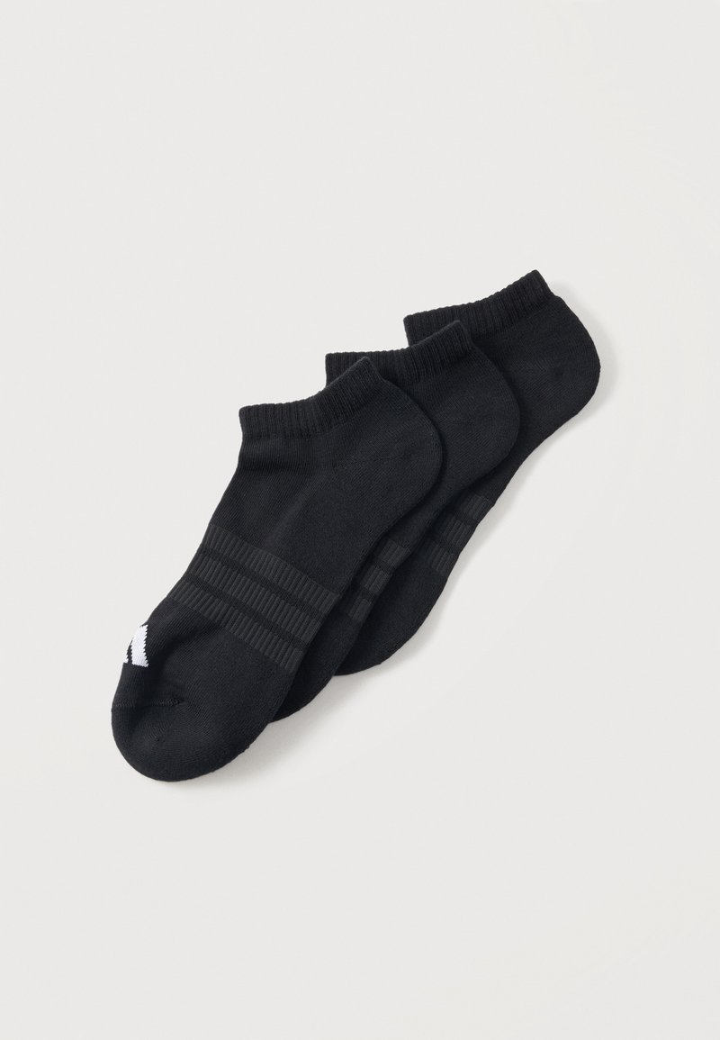 Trois paires de chaussettes courtes noires avec des bords côtelés et un petit logo blanc sur la zone des orteils, posées en chevauchement sur un fond uni clair.