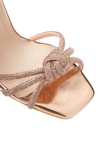 Sandal in oro rosa con tacco alto e punta quadrata, caratterizzata da accenti di perline scintillanti e cinturini intrecciati. Finitura metallica liscia.