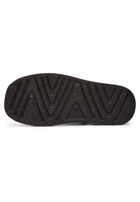 Suola di scarpa in gomma nera con superficie texturizzata, caratterizzata da un motivo a zigzag per la trazione e un bordo liscio.