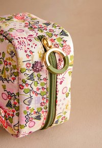 Pastellvärviga püksid lillemustriga, rohelise tõmbluku ja kuldse riistvaraga, ümmargune tõmbluku tõmbejõud, valmistatud pehmest kangast.