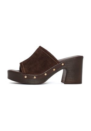 Bruine suède open-toe slip-on mule met blokhak en gouden studs langs de rand van de zool.