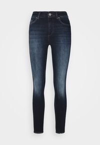 Jeans ajustados en denim azul oscuro, con un diseño de cinco bolsillos, un ligero desgaste y un dobladillo sin rematar en los tobillos. Cierre clásico con botón.