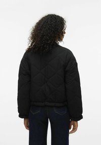 Giacca imbottita nera a trapunta con design corto, polsini a coste e orlo arricciato, mostrata dalla vista posteriore.