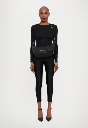 Sac à bandoulière noir en matériau texturé, avec une forme incurvée et un détail de logo doré. À porter en travers du corps avec une sangle ajustable.