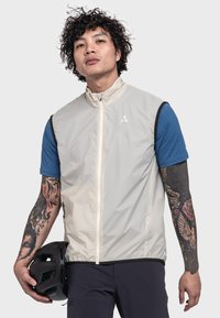 Leichter, ärmelloser Weste in Beige mit hohem Kragen, ausgestattet mit einem Reißverschluss vorne und kontrastierenden schwarzen Akzenten. Über einem blauen Kurzarmhemd getragen.