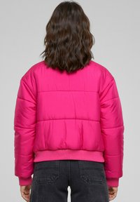 Fuchsia dunjakke med quiltet design, ribbede mansjetter og kant. Har en avslappet passform og avrundede skuldre for komfort.