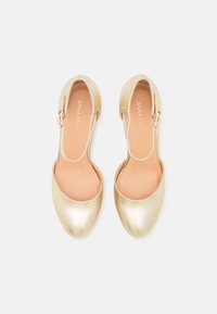 Gold metallic slingback shoes with a rounded toe, smooth texture, and a minimalistic design. Leather insole visible inside.