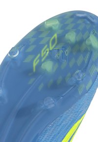 Suola di scarpa da calcio blu con tacchetti rotondi e triangolari, con motivi gialli "F50" e logo Adidas.