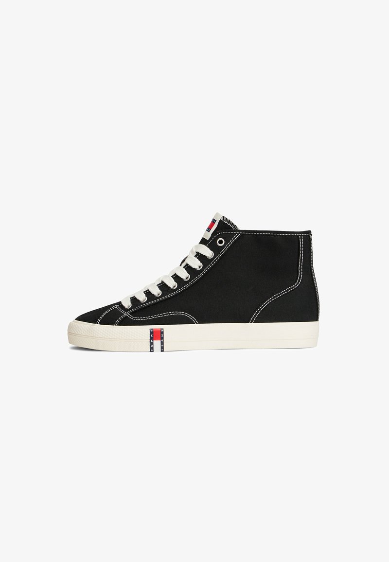 Baskets montantes en toile noire avec coutures blanches, lacets blancs, semelle blanche, et logo Tommy Jeans sur la semelle et la languette.