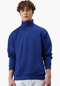Blaue Fleece-Sweatshirt mit hohem Kragen, halbem Reißverschluss und gerippten Bündchen. Hergestellt aus weichem Stoff, bietet eine lockere Passform und ein schlichtes Design.