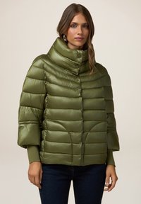 Olivgrüne Puffjacke mit hohem Kragen, horizontalen Steppnähten, Druckknöpfen und Dreiviertelärmeln. Weiche, glänzende Textur.