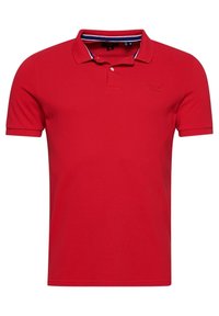 Polo shirt rouge en coton. Présente un col classique, des manches courtes et un petit logo brodé sur la poitrine. Accents en bleu marine et blanc.