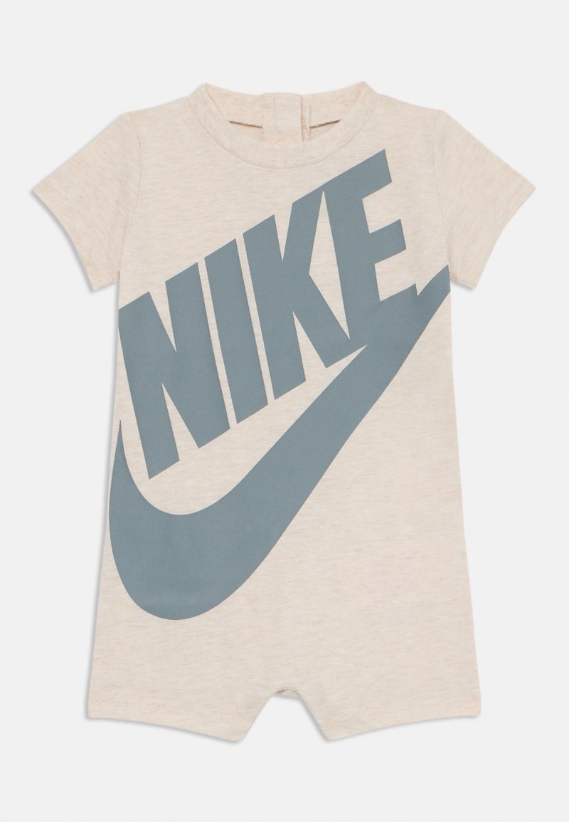 Beige vauvan lyhythihainenhaalari, jossa on suuri harmaa Nike-logo ja swoosh edessä, sekä takana vetoketjukiinnitys.
