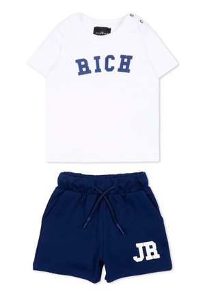Hvid kortærmet skjorte med "RICH" i blå bogstaver og marineblå shorts med snøre og "JR" i hvidt på benet.